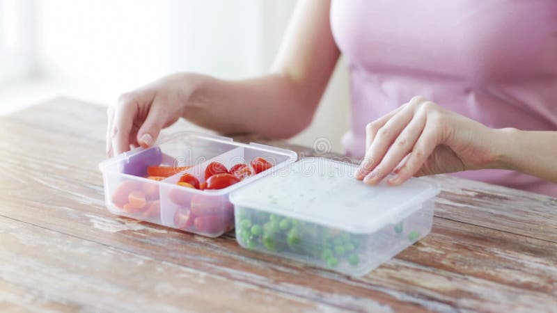 Feche acima da mulher que come vegetais do recipiente