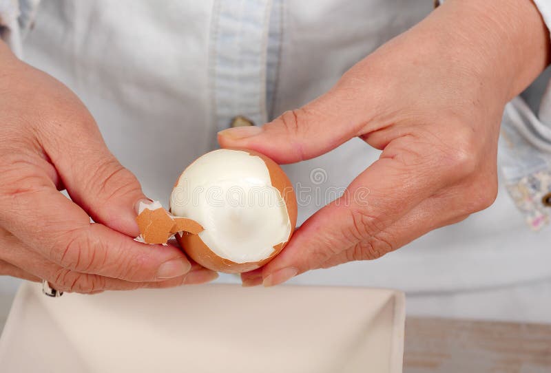 Close up of hands of woman shells a hard-boiled egg. Close up of hands of woman shells a hard-boiled egg