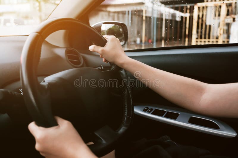 Feche acima das mãos fêmeas que guardam sobre o volante imagem de stock royalty free Feche acima das mãos fêmeas que guardam sobre o volante imagem de stock royalty free