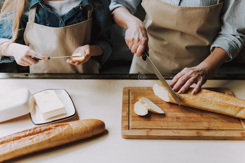 Feche acima das mãos superiores da mulher que cortam o Baguette imagens de stock Feche acima das mãos superiores da mulher que cortam o Baguette imagens de stock