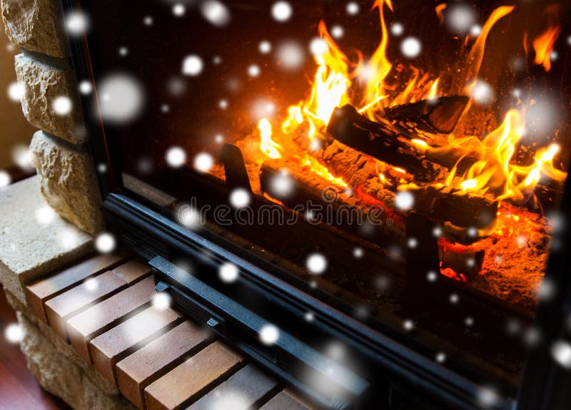 Winter, christmas, warmth, fire and coziness concept - close up of burning fireplace at home with snow. Winter, christmas, warmth, fire and coziness concept - close up of burning fireplace at home with snow
