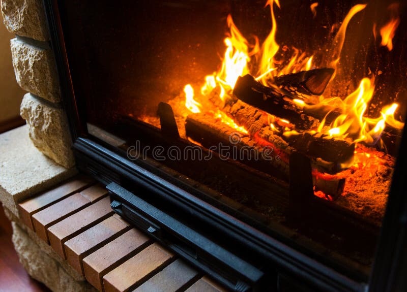 Heating, warmth, fire and cosiness concept - close up of burning fireplace at home. Heating, warmth, fire and cosiness concept - close up of burning fireplace at home