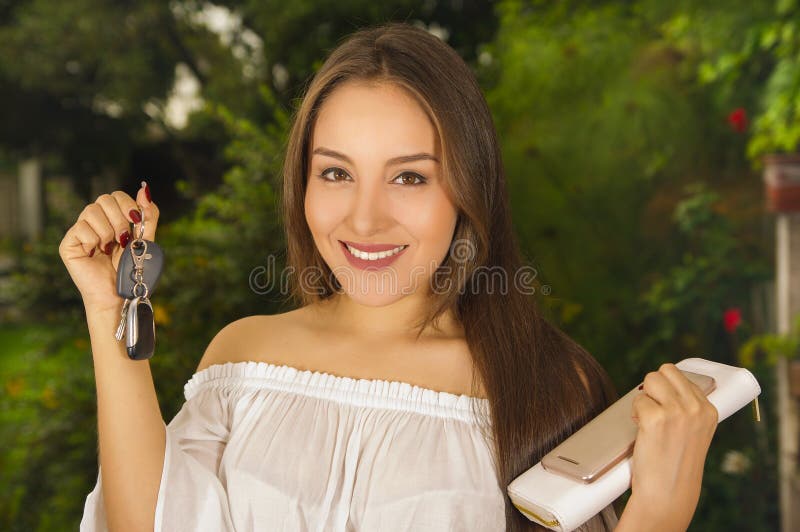 Feche acima de uma jovem mulher bonita de sorriso que guarda suas chaves em uma mão e a tabuleta e a bolsa em sua outra mão dentr foto de stock royalty free Feche acima de uma jovem mulher bonita de sorriso que guarda suas chaves em uma mão e a tabuleta e a bolsa em sua outra mão dentr foto de stock royalty free