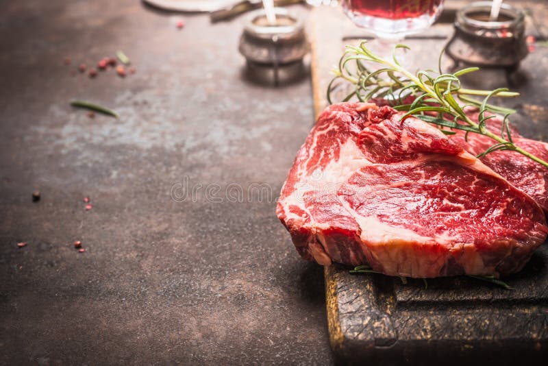 Feche acima do bife cru de Ribeye da carne fresca com ervas e especiarias no fundo rústico escuro do metal fotografia de stock Feche acima do bife cru de Ribeye da carne fresca com ervas e especiarias no fundo rústico escuro do metal fotografia de stock