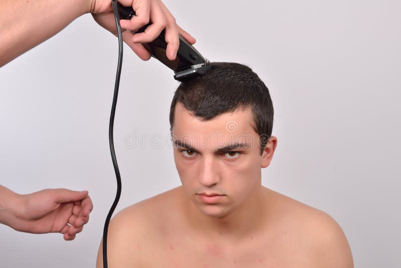 Feche acima do estudante masculino que tem um corte de cabelo com tosquiadeiras de cabelo fotografia de stock Feche acima do estudante masculino que tem um corte de cabelo com tosquiadeiras de cabelo fotografia de stock