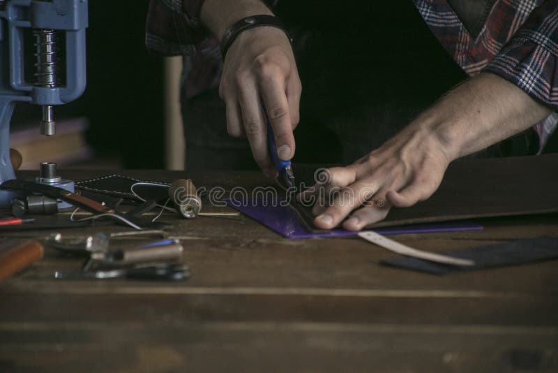 Feche acima do fabricante do couro da mão do homem que trabalha na tabela de madeira com ferramentas imagem de stock royalty free Feche acima do fabricante do couro da mão do homem que trabalha na tabela de madeira com ferramentas imagem de stock royalty free