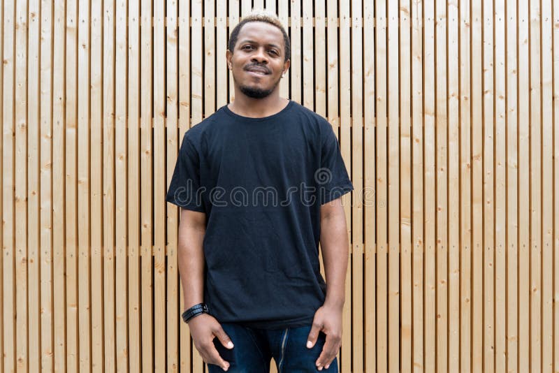 Feche acima do homem de pele escura atrativo no t-shirt preto no fundo de madeira fotos de stock royalty free Feche acima do homem de pele escura atrativo no t-shirt preto no fundo de madeira fotos de stock royalty free