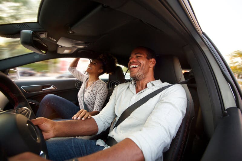 Feche acima do homem e da mulher que sorriem e que sentam-se junto no automóvel fotos de stock Feche acima do homem e da mulher que sorriem e que sentam-se junto no automóvel fotos de stock