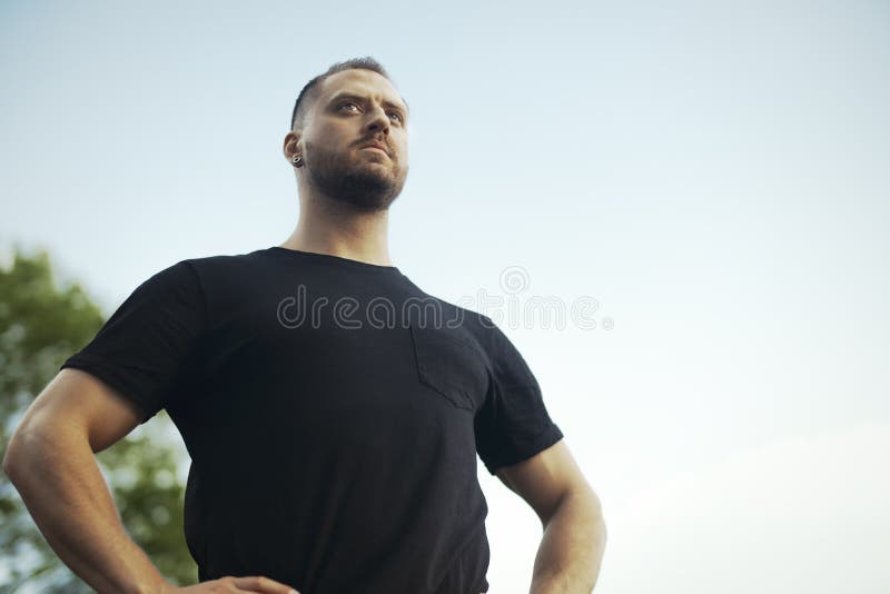 Feche acima do homem novo no sportswear preto que relaxa no parque após o exercício imagens de stock royalty free Feche acima do homem novo no sportswear preto que relaxa no parque após o exercício imagens de stock royalty free