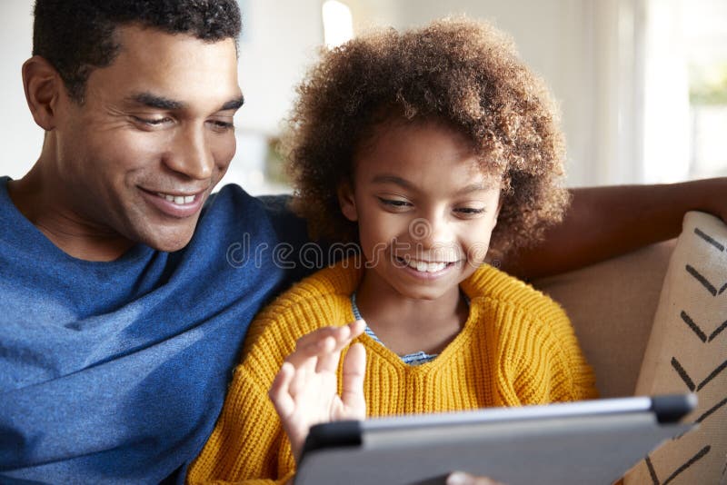 Feche acima do pai e da filha que usa o tablet pc junto, sentando-se no sofá na sala de visitas, foco seletivo fotos de stock Feche acima do pai e da filha que usa o tablet pc junto, sentando-se no sofá na sala de visitas, foco seletivo fotos de stock