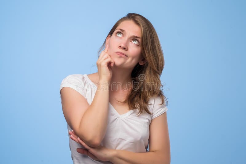 Feche acima do retrato da menina pensativa consideravelmente segura que olha como o conspirador que está sobre o fundo cinzento fotografia de stock royalty free Feche acima do retrato da menina pensativa consideravelmente segura que olha como o conspirador que está sobre o fundo cinzento fotografia de stock royalty free