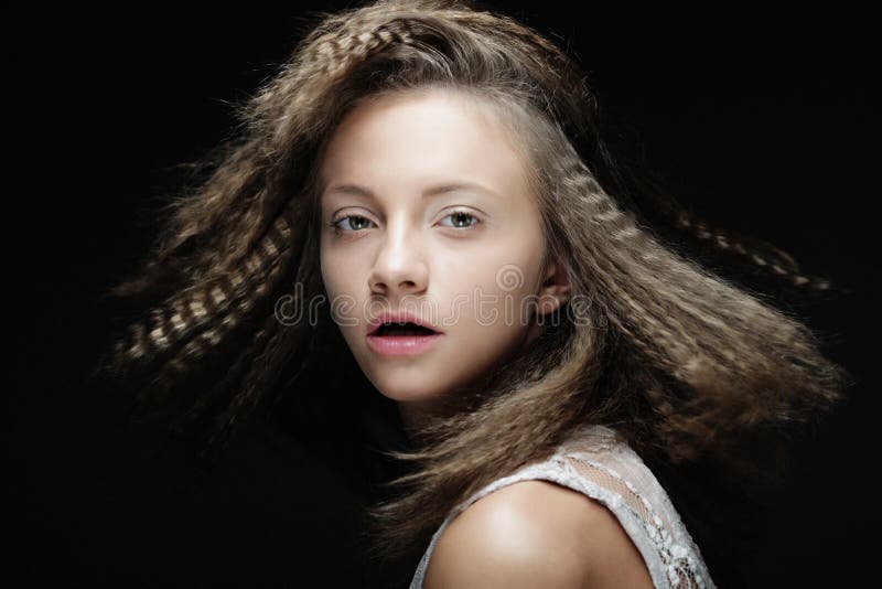 Feche acima do retrato da mulher loura nova com cabelo encaracolado sobre o fundo preto fotografia de stock Feche acima do retrato da mulher loura nova com cabelo encaracolado sobre o fundo preto fotografia de stock