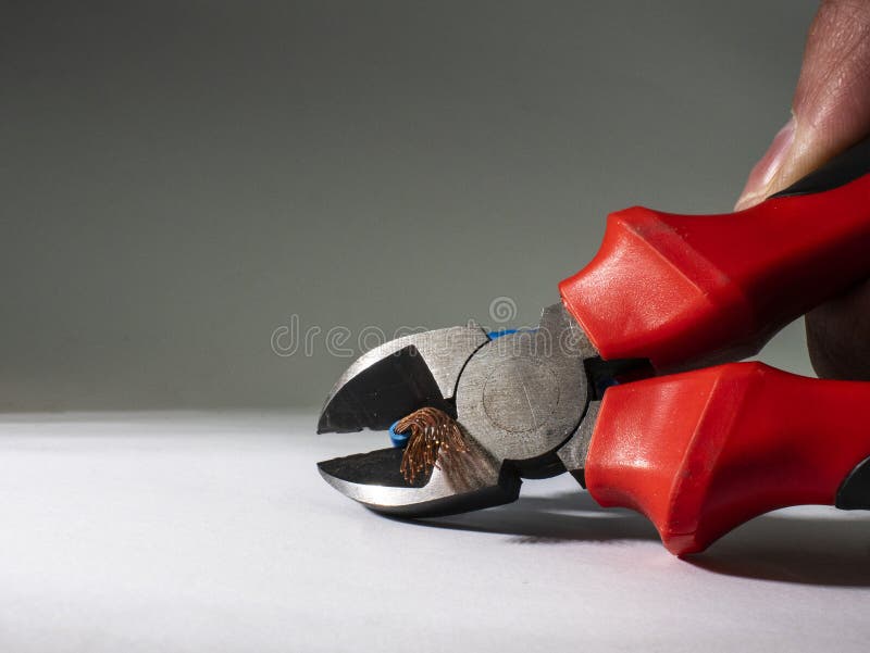 Feche acima dos alicates vermelhos e do fio torcido azul no fundo branco Alicates que cortam o cabo foto de stock royalty free Feche acima dos alicates vermelhos e do fio torcido azul no fundo branco Alicates que cortam o cabo foto de stock royalty free