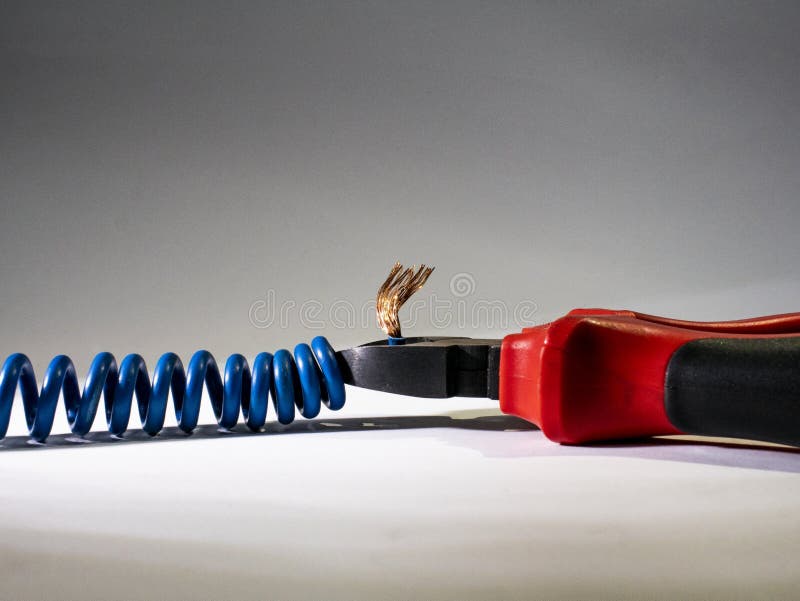 Feche acima dos alicates vermelhos e do fio torcido azul no fundo branco Alicates que cortam o cabo imagens de stock Feche acima dos alicates vermelhos e do fio torcido azul no fundo branco Alicates que cortam o cabo imagens de stock