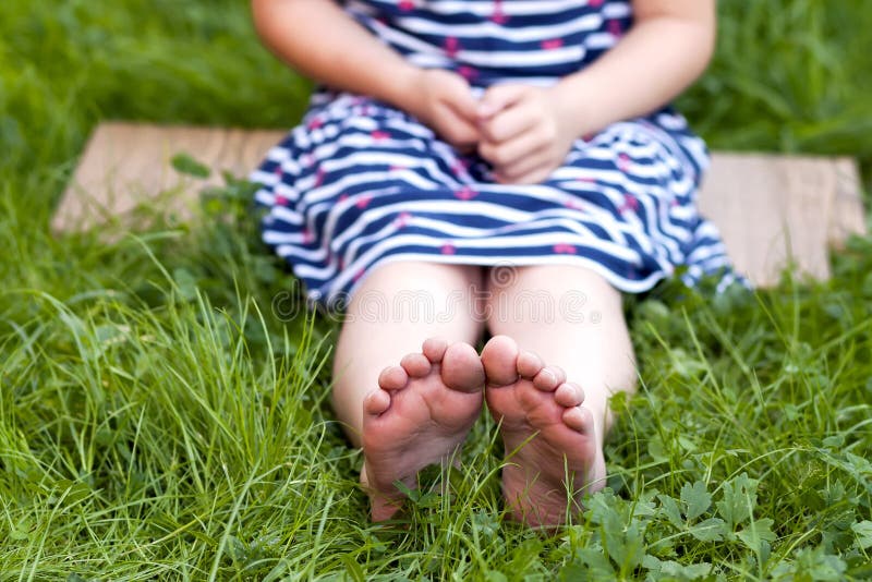 Feche acima dos pés da menina na grama verde fotografia de stock Feche acima dos pés da menina na grama verde fotografia de stock