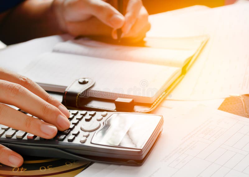 Feche acima, homem de negócio ou contador do advogado que trabalham em contas usando uma calculadora e escrevendo em originais