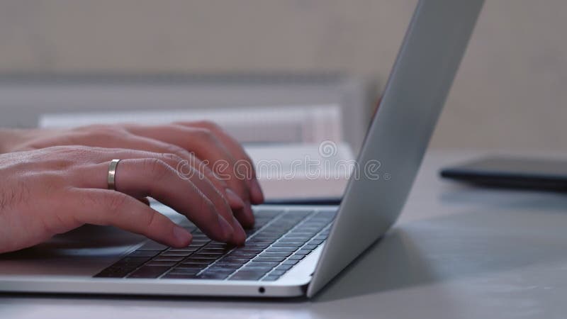 Feche as mãos de um homem digitando em um laptop