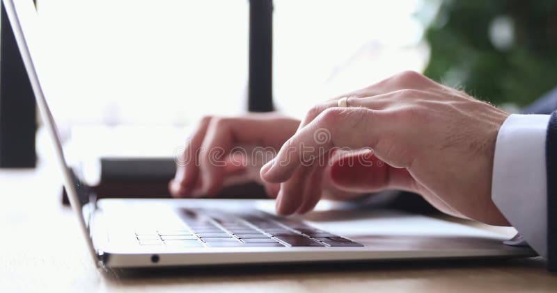 Feche as mãos masculinas digitando mensagem no teclado do laptop.