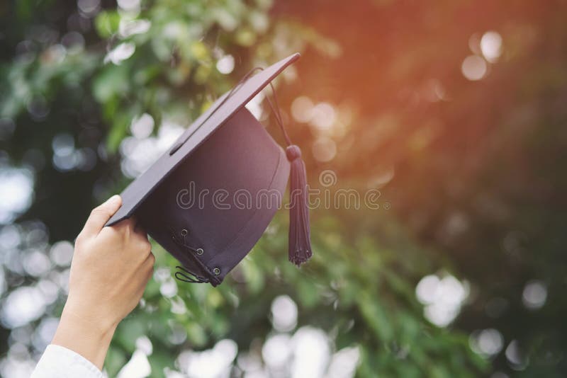 Close up people graduate show hand hold show hat in background outdoor. Shot of graduation cap during Commencement University Degree Concept , Celebration Education Student Success Learning Concept. Close up people graduate show hand hold show hat in background outdoor. Shot of graduation cap during Commencement University Degree Concept , Celebration Education Student Success Learning Concept.