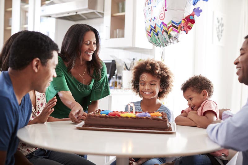 Feche a família de três gerações sentadas à mesa da cozinha celebrando o aniversário da filha pré-adolescente ? com um bi