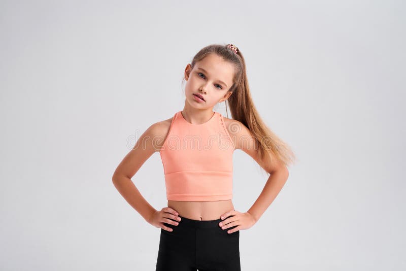 Feeling good. Flexible cute little girl child looking at camera while doing exercise isolated on a white background