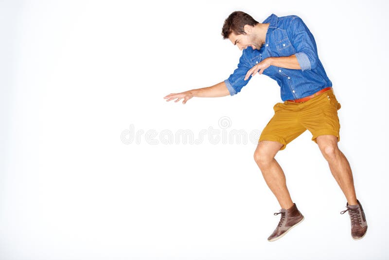 Feeling a little crazy. Stylish young guy jumping expressively against a white background. stock photo