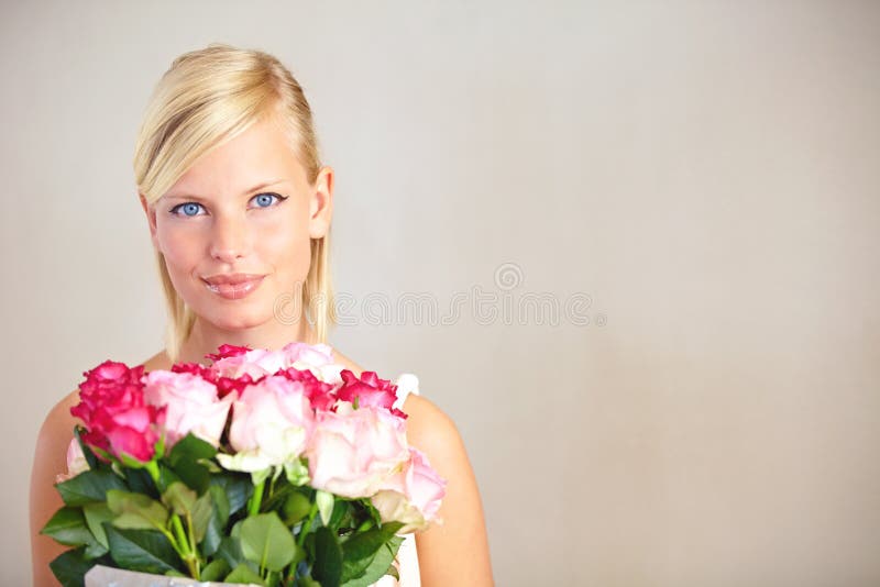 Feeling loved and appreciated. Portrait of a young woman holding a bouquet of pink roses.