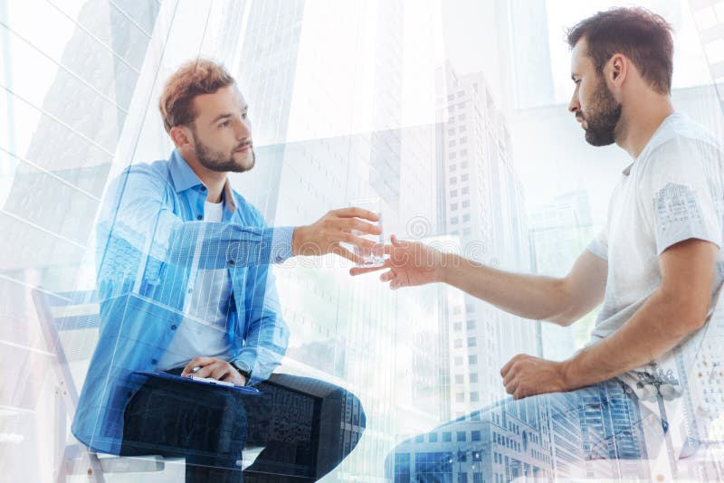 Attentive psychiatrist giving a glass of water to his patient stock photo Attentive psychiatrist giving a glass of water to his patient stock photo