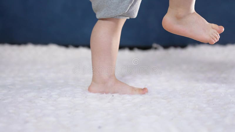 feet baby a learns to indoor walk. first steps of a newborn close-up at home. baby feet kicking learns to walk. A cute