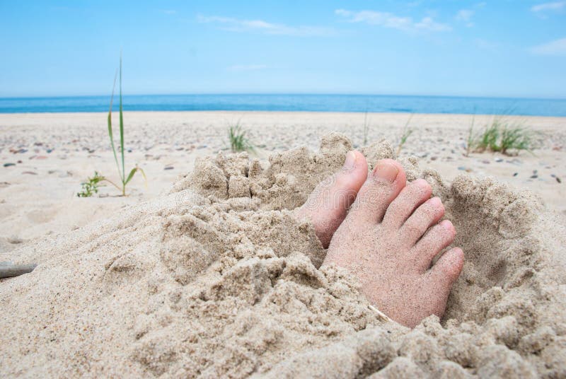 Feet buried in sand with uncovered toes on a beach. Feet buried in sand with uncovered toes on a beach