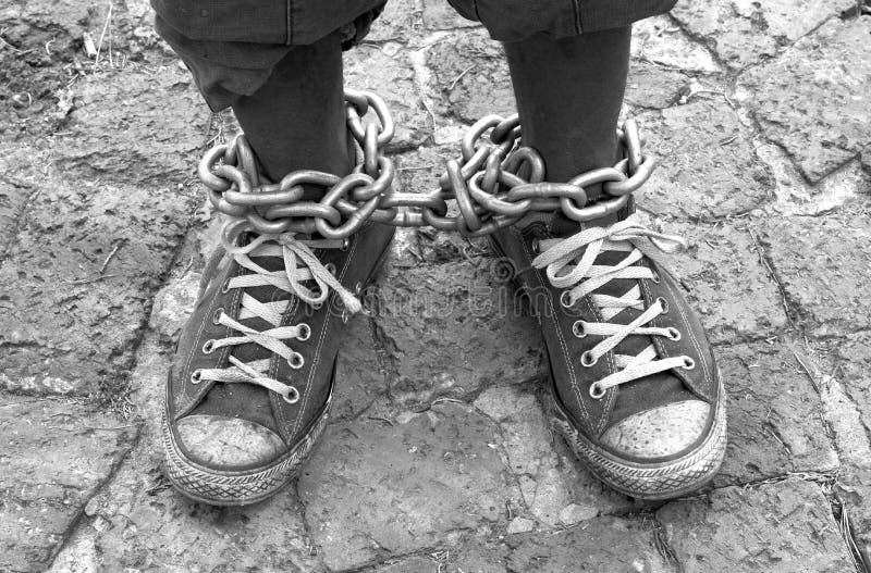 Vista dall'alto su due incatenato nero in piedi con le vecchie scarpe sporche di un Sud Africano Xhosa uomo, in piedi sul marciapiede.