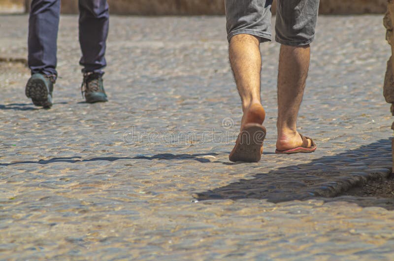 Feet with Different Types of Shoes from Passersby on a Pebbly Sidewalk