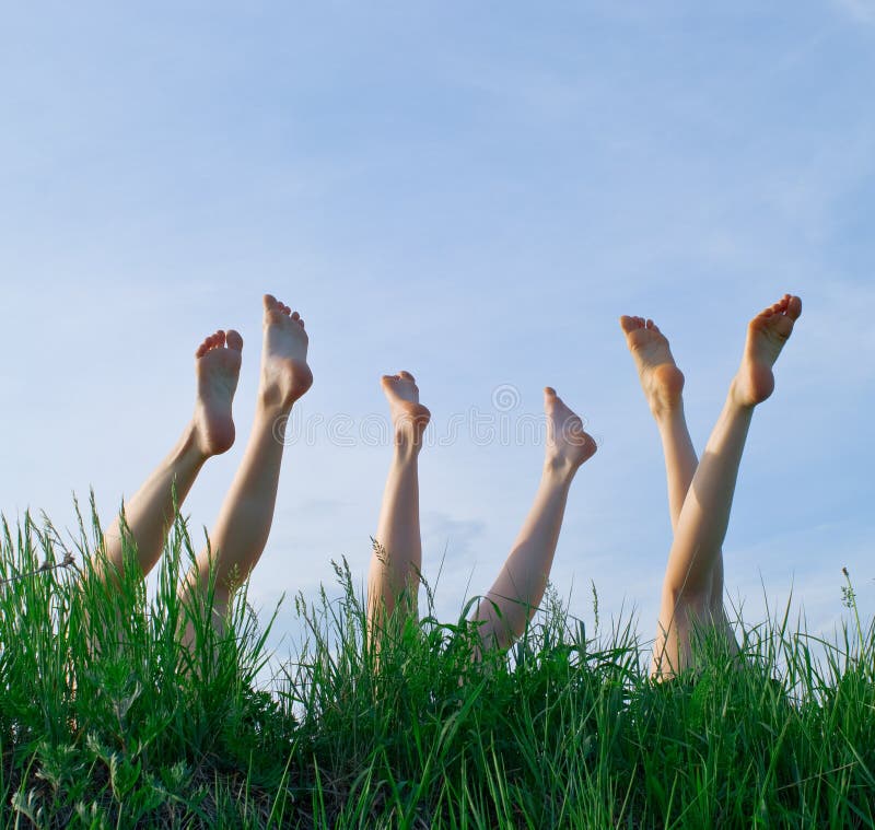 Feet of girls laying and sunbathing in a grass