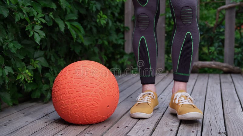 Feet and legs of muscular man in compression tights exercising with a slam ball