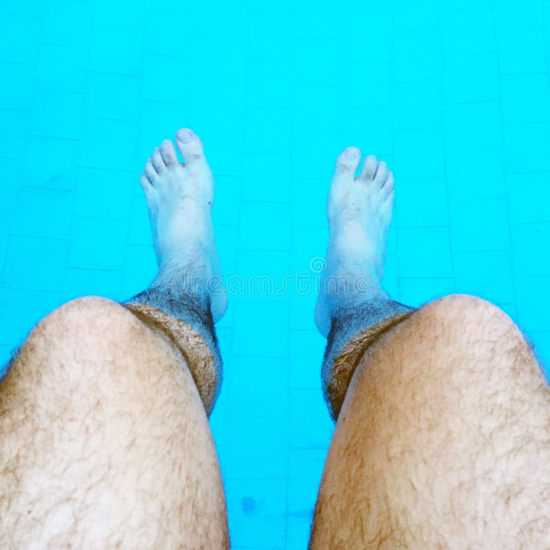 Man dipping his feet in a pool during summertime on vacation