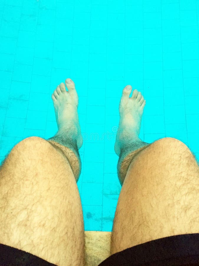 Man dipping his feet in a pool during summertime on vacation