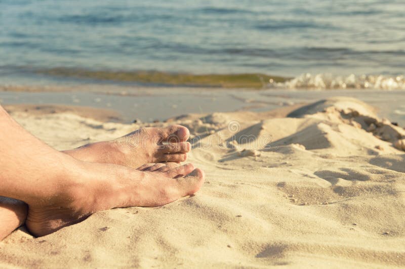 Feet of man lie on sand stock photography