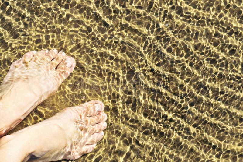 Bare feet wading in clear shallow water at sandy beach. Bare feet wading in clear shallow water at sandy beach