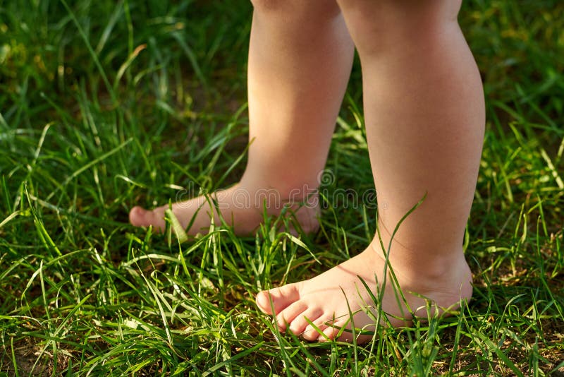 The feet of a small child on the grass, walking on bumps