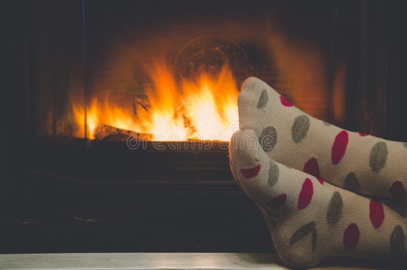 Feet in socks of all the family warming by cozy fire stock images