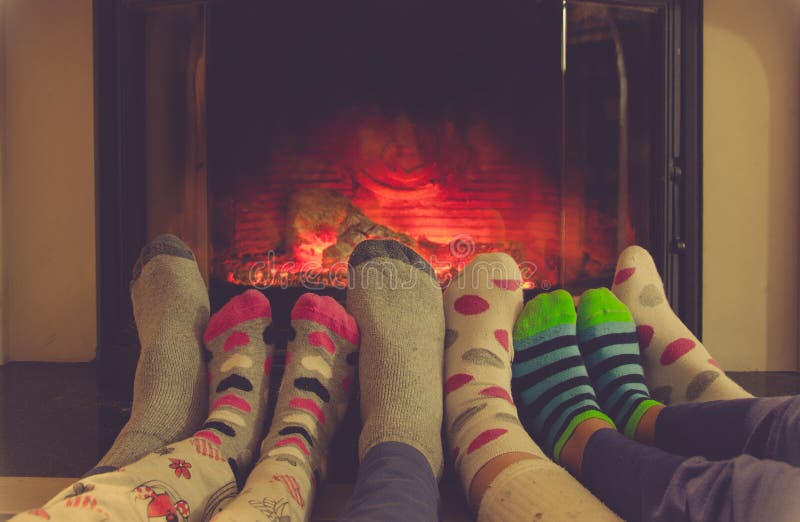 Feet in socks of all the family warming by cozy fire stock photo
