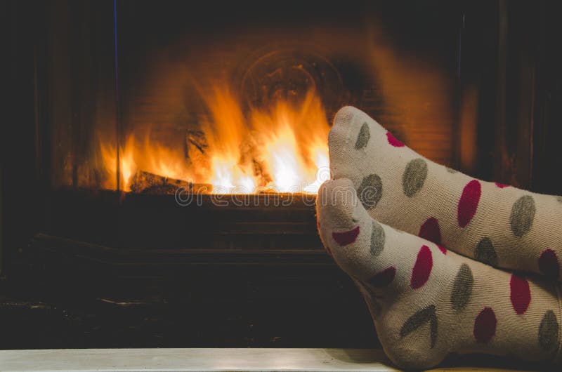 Feet in socks of all the family warming by cozy fire stock image