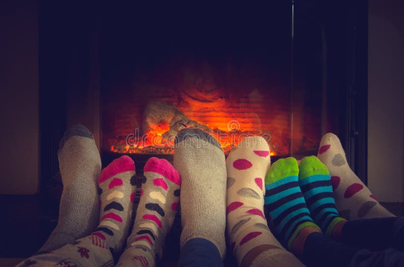 Feet in socks of all the family warming by cozy fire royalty free stock photo