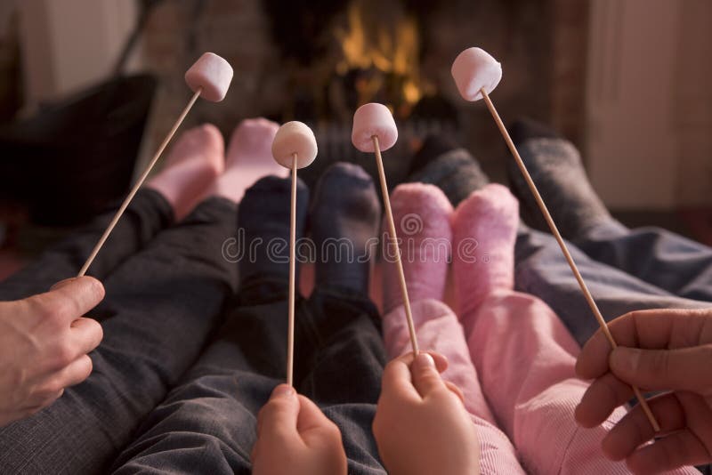 Feet warming at a fireplace with marshmallows