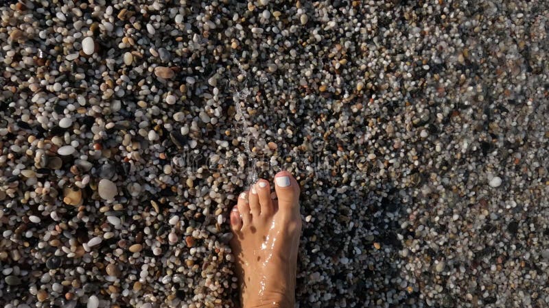 Feet of a woman walking along the waters edge