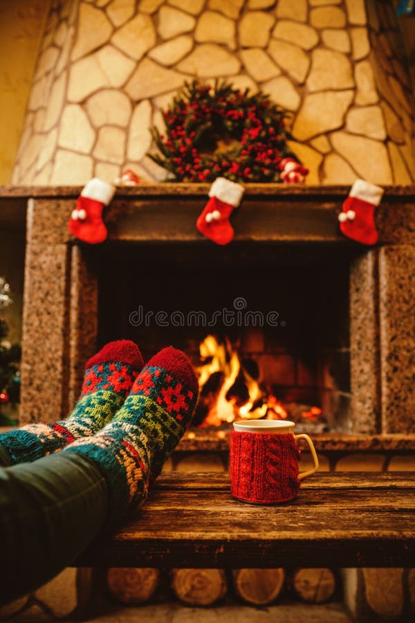 Feet in woollen socks by the Christmas fireplace. Woman relaxes royalty free stock photography Feet in woollen socks by the Christmas fireplace. Woman relaxes royalty free stock photography