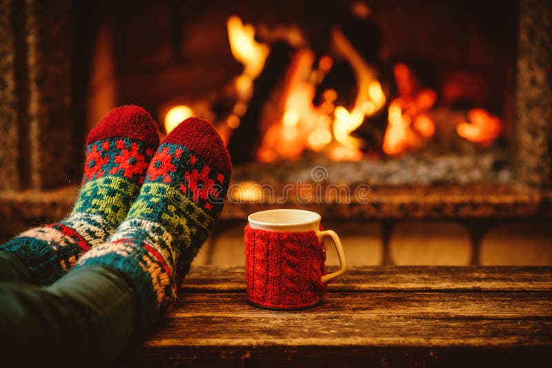 Feet in woollen socks by the Christmas fireplace. Woman relaxes