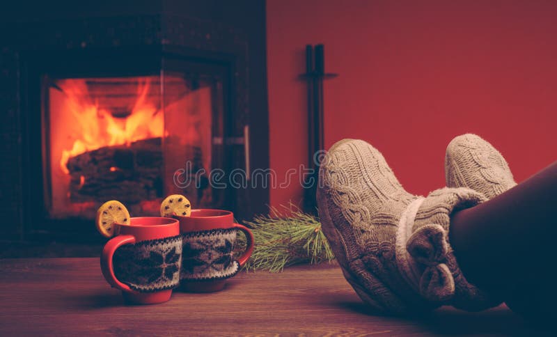 Feet in woollen socks by the Christmas fireplace. Woman relaxes royalty free stock image Feet in woollen socks by the Christmas fireplace. Woman relaxes royalty free stock image