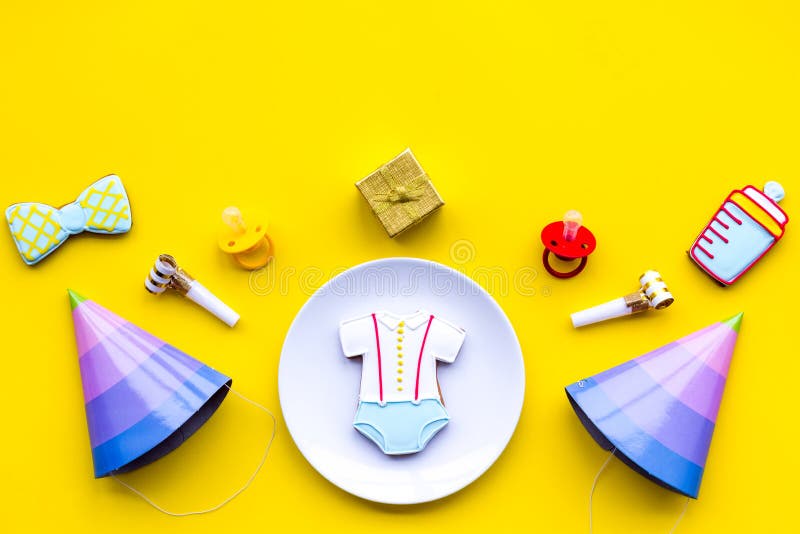 Feiern Sie Kind-` s Geburtstag Plätzchen in Form des Babyzubehörs, Parteihüte, Geschenkbox auf Draufsicht des gelben Hintergrunde stockbild Feiern Sie Kind-` s Geburtstag Plätzchen in Form des Babyzubehörs, Parteihüte, Geschenkbox auf Draufsicht des gelben Hintergrunde stockbild