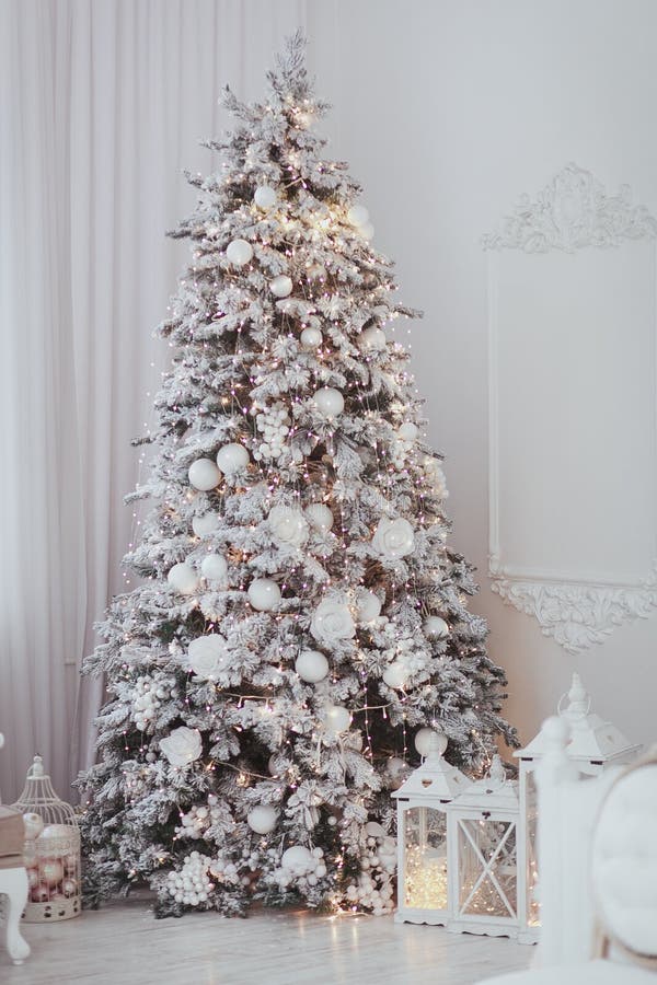 Feiertag verzierte Raum mit dem Weihnachtsbaum, der mit Schnee und Spielwaren bedeckt wurde Weißer Innenraum mit Lichtern